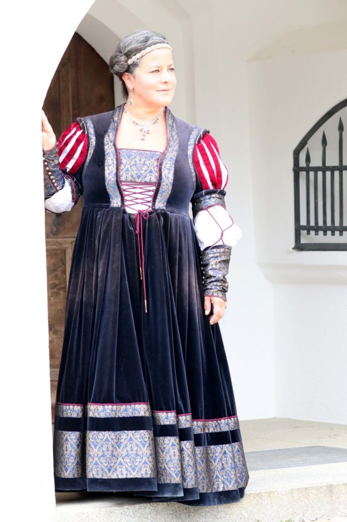 Eine Frau trägt ein handgenähtes Mittelalter-Kleid aus Samt.